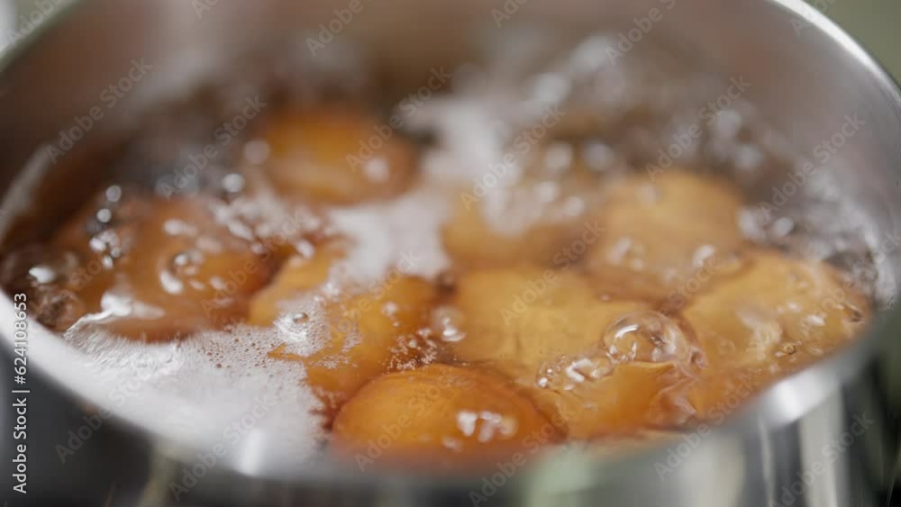 dozen eggs elegantly boil in a simmering pot. The bubbling water gently