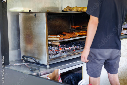 Bratwursts are prepared on a charcoal grill