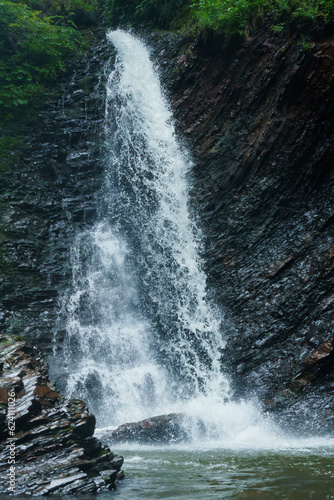 Mountain waterfall  large water flow of mountain waterfall  mountain river near the rock. Huk Waterfall  Ukrainian Carpathians