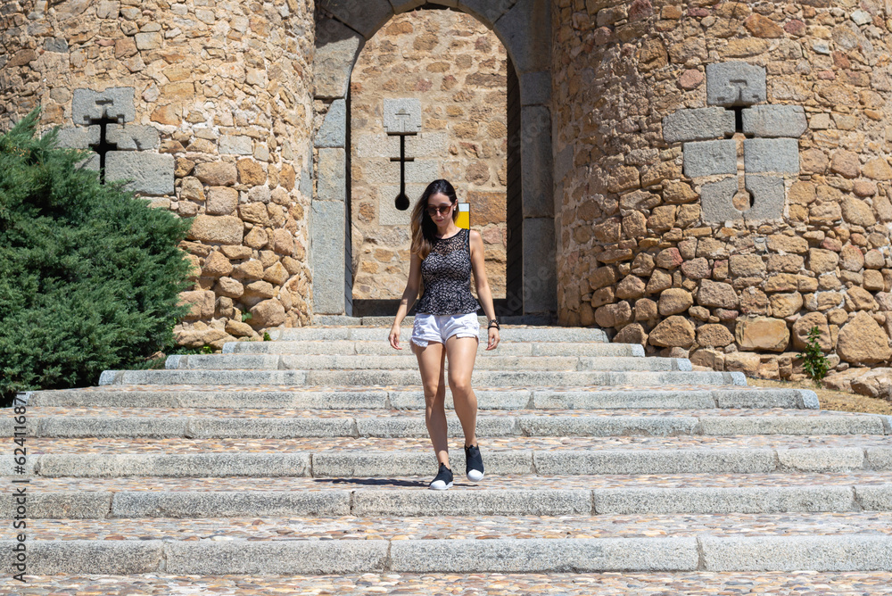 Beautiful young woman using sunglasses walking down a staircase at Mazanares El Real Castle in Spain.