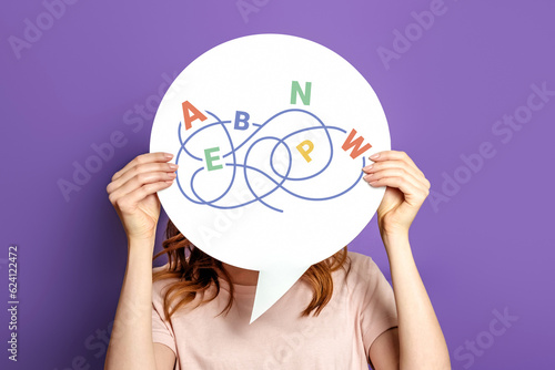 Dyslexia concept. Girl holding a poster with the image of letters isolated on a lilac background photo