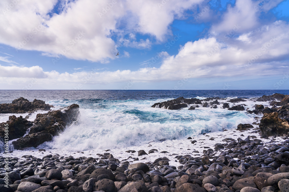 Water breaks on pebbles and rocks on an empty beach in the Atlantic Ocean
