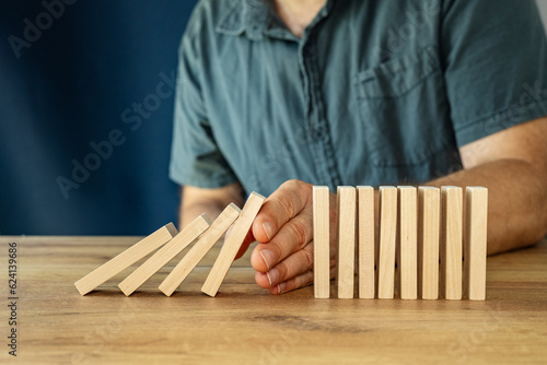the hand of an efficient manager  stop falling off wood block, planing and strategy concept, business disruption, company restructuring, action needed