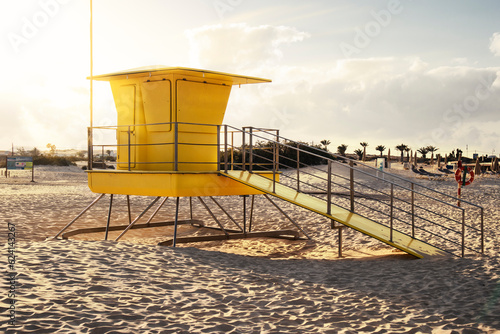 Yellow beach watchtower on a white sandy beach, bathed by the sun's rays at sunset. Fuerteventura, Canary Islands, Spain © Jess