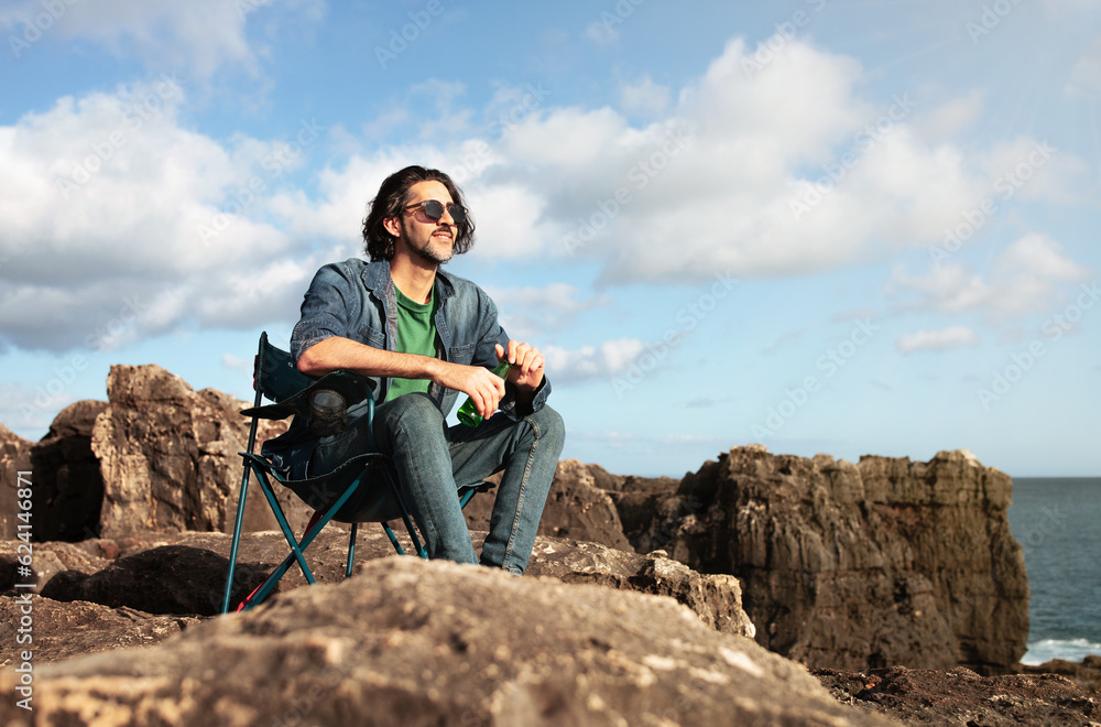 Portrait Of Dreamy Young Man Sitting On Beach Rocks Near Ocean Portrait Of Dreamy Young Man Sitting On Beach Rocks Near Ocean
