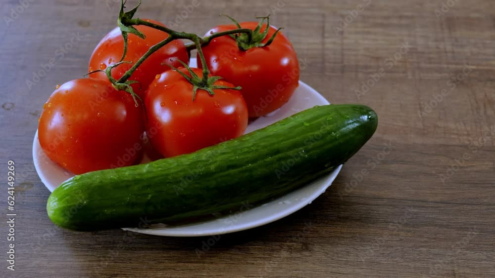 red tomatoes and green cucumber in a white plate on the table red tomatoes and green cucumber in a white plate on the table