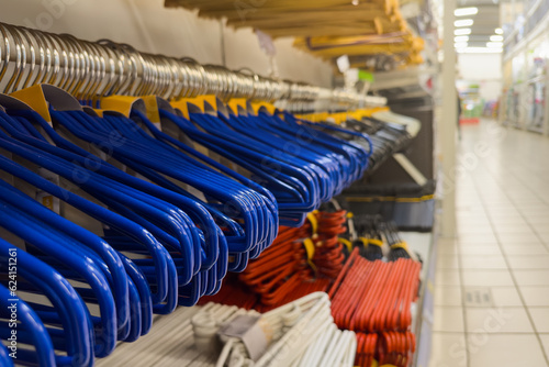Lots of empty hangers in the store. Row of empty hangers in blue in a store close-up. Copy space. The concept of a sale or shortage of goods. © AGSOL