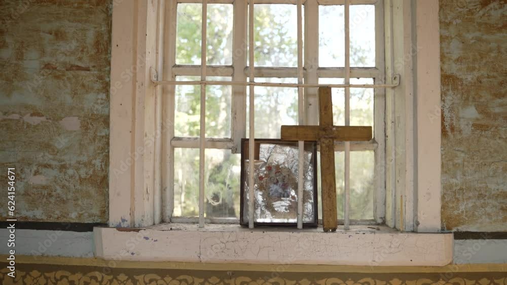 A grimy window with sturdy bars, a forgotten icon and cross in abandoned church. A grimy window with sturdy bars, a forgotten icon and cross in abandoned church.