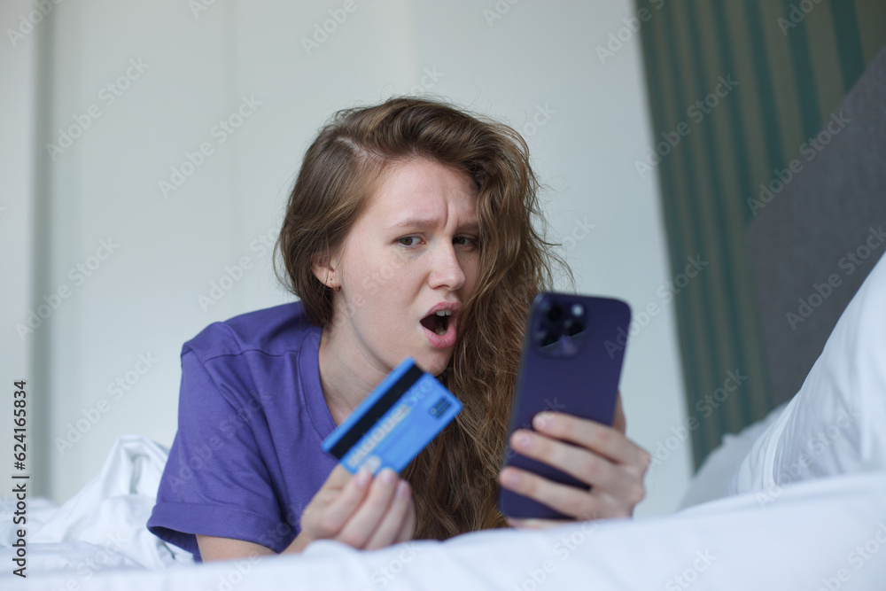 young woman with credit bank card and cell mobile phone, smartphone at home in living room young woman with credit bank card and cell mobile phone, smartphone at home in living room