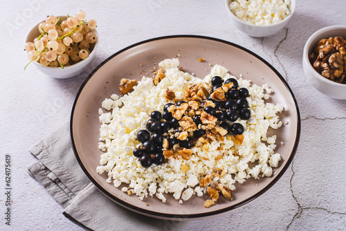 Homemade cottage cheese with fresh blackcurrants and walnuts on a plate