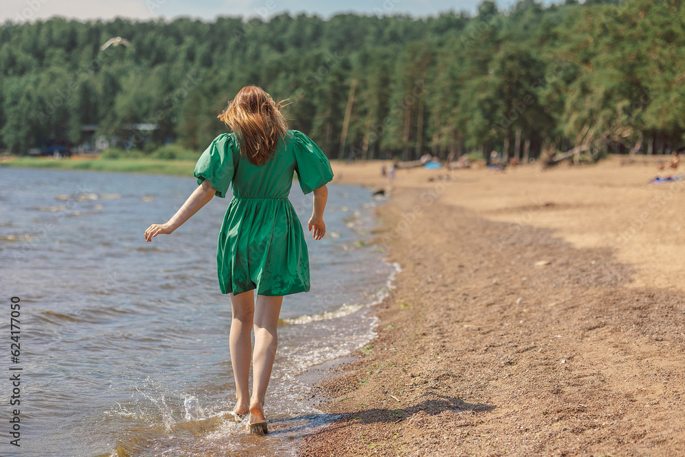 Happy teenage girl walking along coastline.Girl playing with water, splashing on beach on holidays. High quality photo Happy teenage girl walking along coastline.Girl playing with water, splashing on beach on holidays. High quality photo