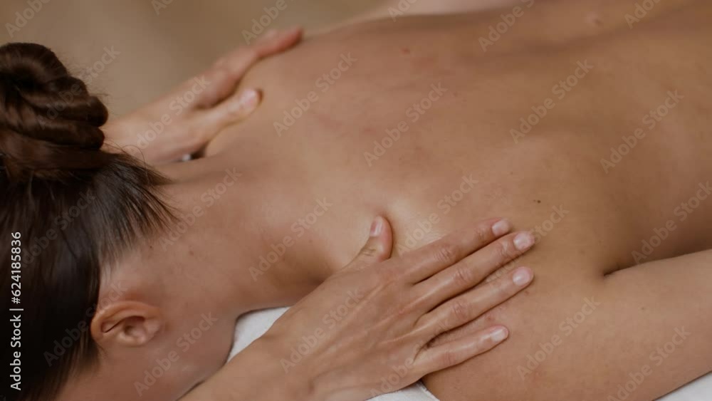 Unrecognizable young woman lying on massage couch in spa, professional masseur hands massaging female body Unrecognizable young woman lying on massage couch in spa, professional masseur hands massaging female body