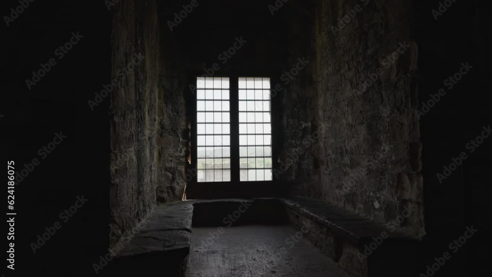 Walking handheld through a dark room with stone walls in Conwy Castle toward a brightly lit window, on a spring afternoon, in Conwy, Wales, UK Walking handheld through a dark room with stone walls in Conwy Castle toward a brightly lit window, on a spring afternoon, in Conwy, Wales, UK