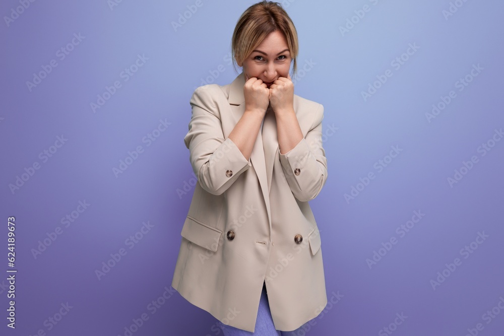 pensive blond millennial woman in stylish jacket thinks about business on studio background with copy space pensive blond millennial woman in stylish jacket thinks about business on studio background with copy space