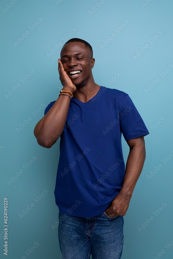 pleasant well-groomed cute young african man in a blue t-shirt on a blue background pleasant well-groomed cute young african man in a blue t-shirt on a blue background