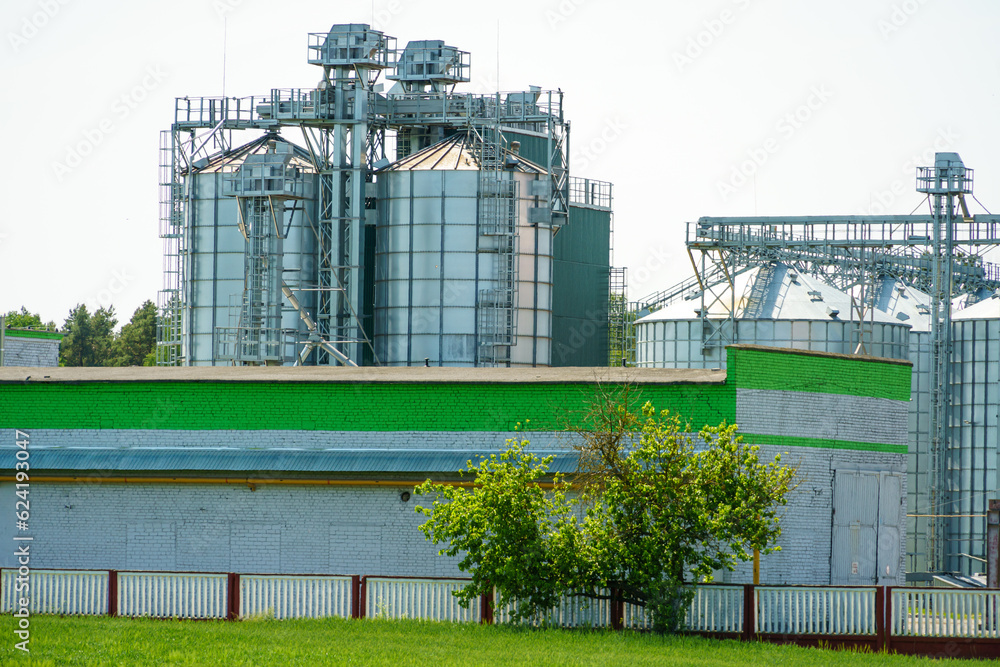 Fototapeta premium A large modern plant for the storage and processing of grain crops. view of the granary on a sunny day against the blue sky. End of harvest season.