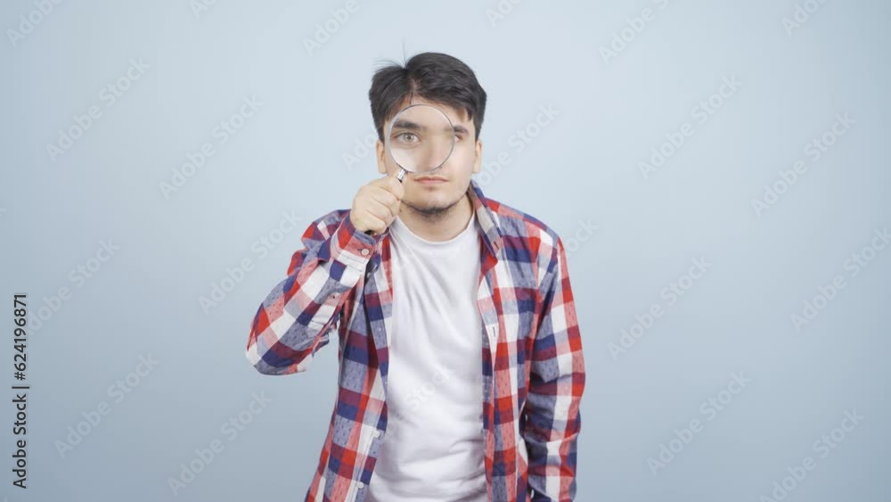 Man looking at camera with magnifying glass. Man looking at camera with magnifying glass.