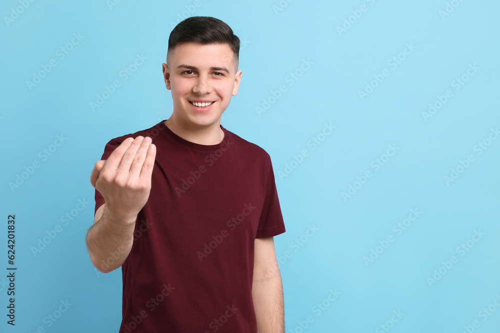 Handsome man inviting to come in against light blue background. Space for text Handsome man inviting to come in against light blue background. Space for text
