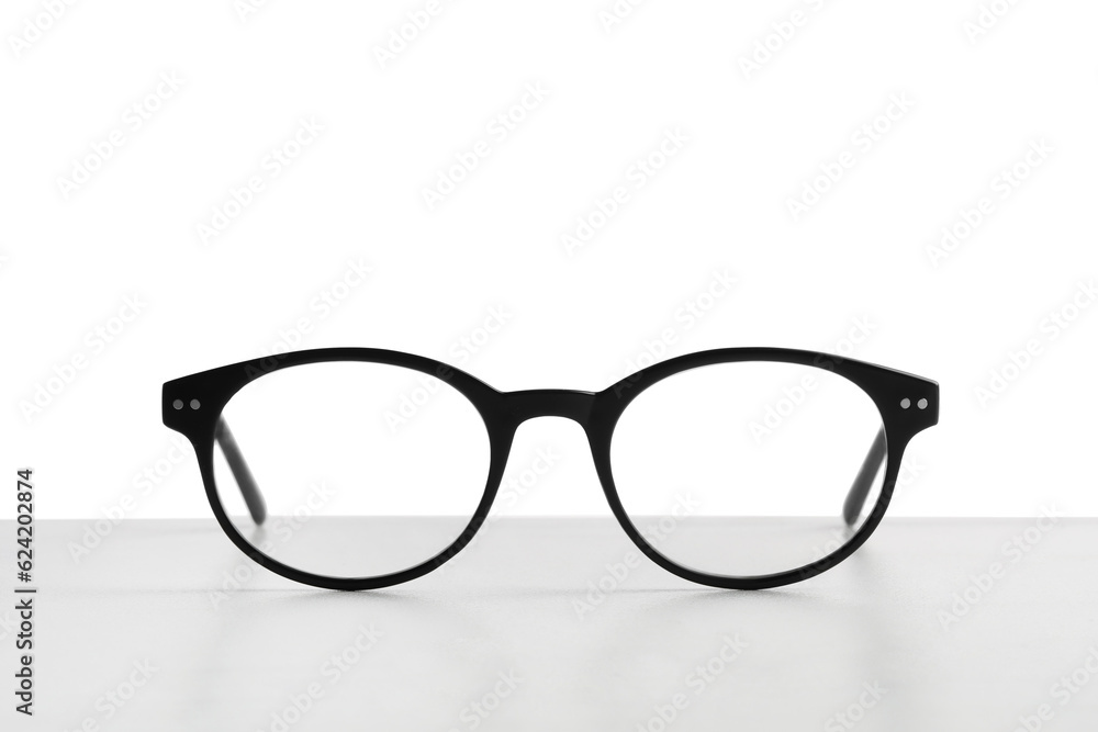 Stylish glasses with black frame on table against white background Stylish glasses with black frame on table against white background