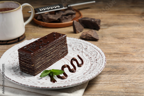 Tasty Spartak cake and mint on wooden table, space for text photo