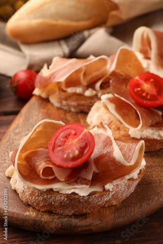 Board of tasty sandwiches with cured ham, tomato and cream cheese on table, closeup