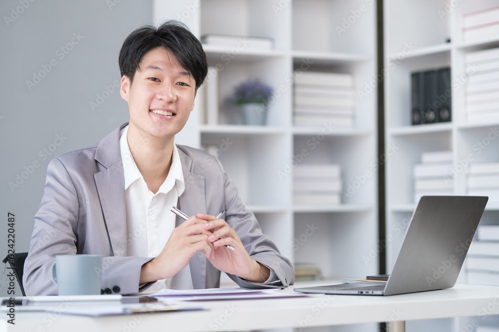 Portrait of asian businessman office worker sitting at desk and smiling to camera. Portrait of asian businessman office worker sitting at desk and smiling to camera.