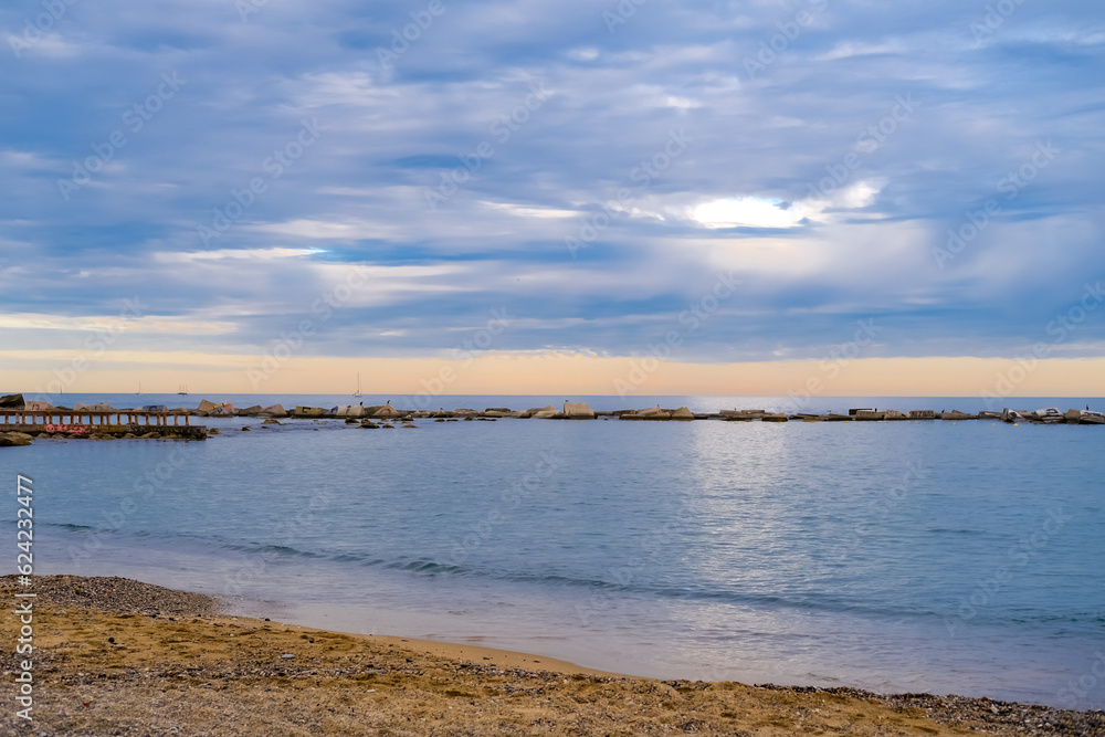 Calm seascape of the Mediterranean coast. View of the sea, the ocean. Time after sunset A beautiful blue color of water and sky, an orange stripe of sunset on the horizon.