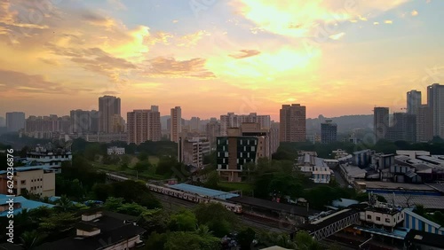 Aerial 4k city view of suburban Mumbai during a beautiful sunset revealing dense city. Mumbai drone at sunset with local railway train. Cinematic drone shot of Indian city with building rooftop 