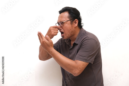 asian man expression covers nose smells bad photo