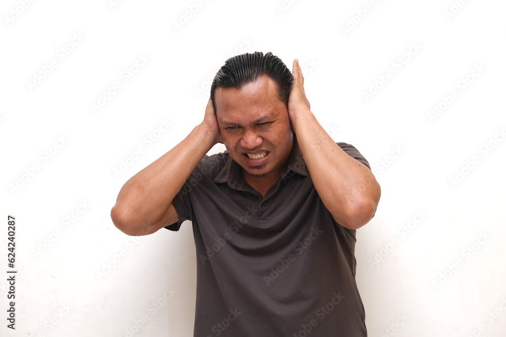 Asian man covers ears to avoid noise Asian man covers ears to avoid noise