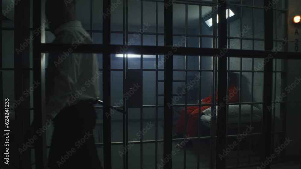 prison-officer-with-police-baton-watches-criminals-in-prison-cells