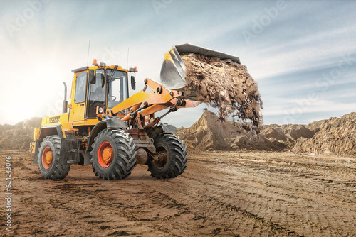 Wheel front loader bulldozer pours sand. Distributes sand for road construction. Powerful earthmoving equipment. Construction site. Rental of construction equipment.