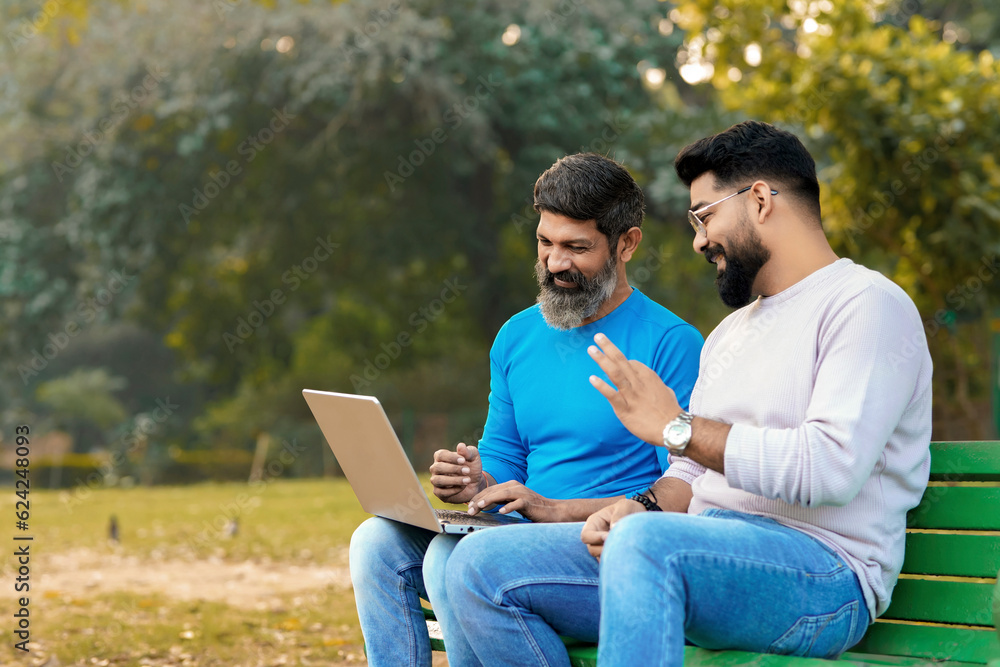 Two indian male discuss and using laptop at park