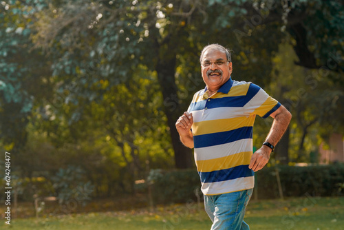 Indian old man running or jogging at park