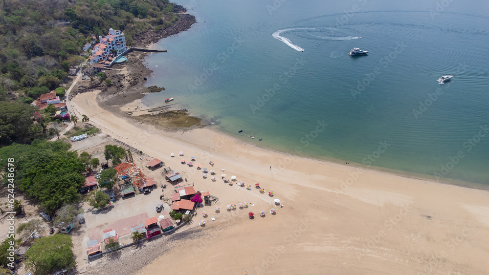 Aerial drone panorama of the sand beach and island of Taboga, popular getaway spot close to Panama city. Visible tourist stalls and bars, together with sandy beach.