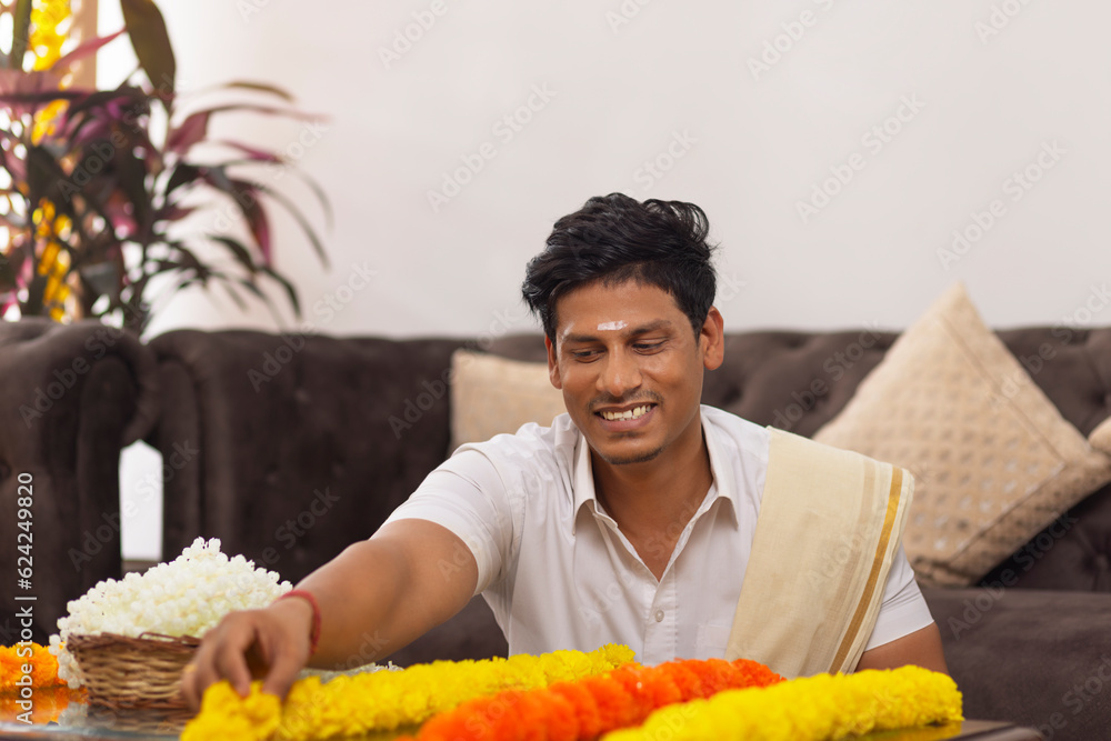 Φωτογραφία South Indian man in white shirt garlanding flowers to celebrate Onam
