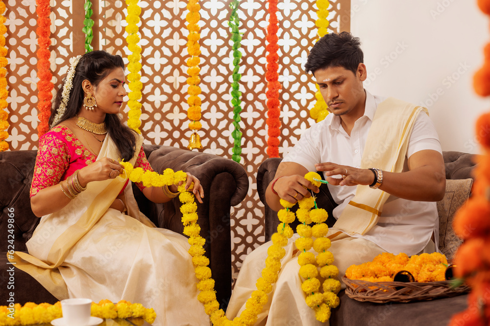Φωτογραφία South Indian couple garlanding flowers together at home to celebrate Onam