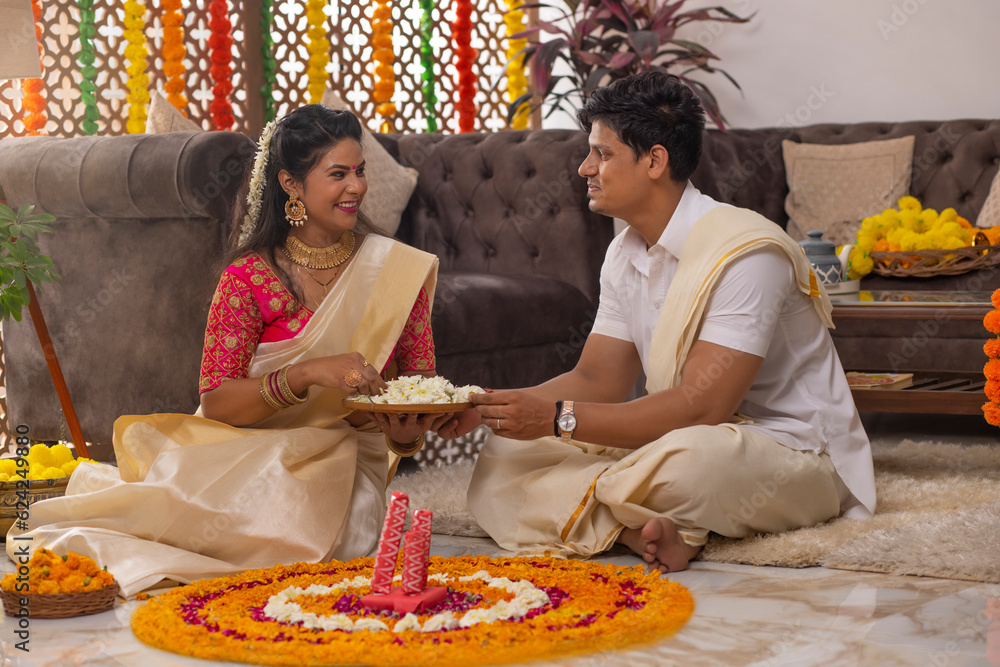Φωτογραφία South Indian couple decorating house with flower garland to celebrate Onam