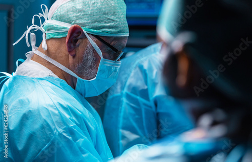 Fototapete Team of medical doctors performs surgical operation in modern operating room using high-tech technology