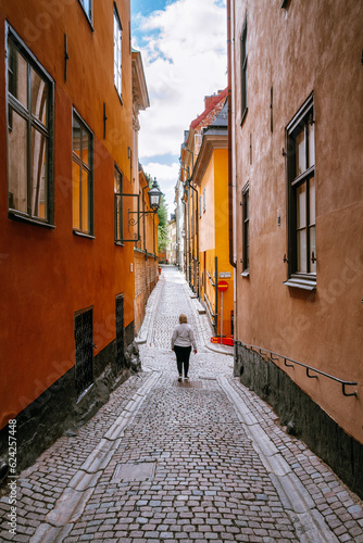 Woman walking down a colorful cobble lane in the old town of Stockholm in Sweden