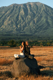 A guy and a girl, of European appearance, do yoga, meditate with their eyes closed, hands clasped in Namaste, in nature, against the backdrop of a mountain.