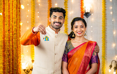 Happy young indian couple showing new home keys by looking at camera home - concept of new festival purchase, investment planning and family relationship