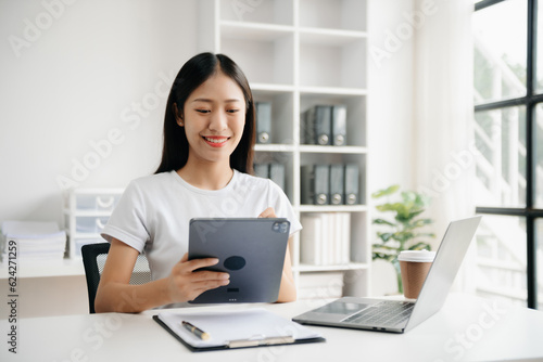 Business woman using tablet and laptop for doing math finance on an office desk, tax, report, accounting, statistics, and analytical research concept in office