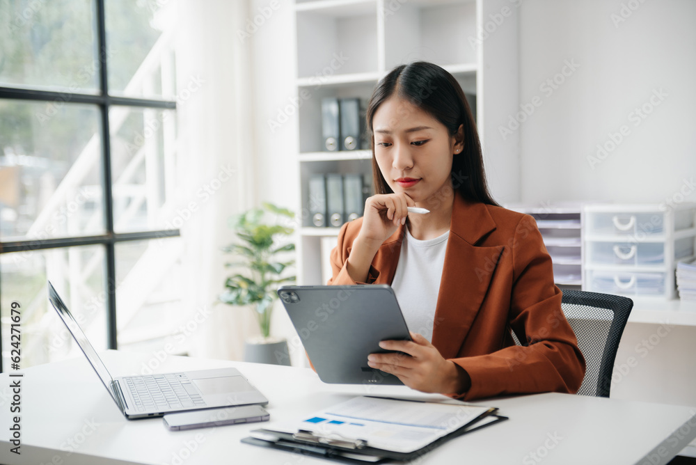 Business woman using tablet and laptop for doing math finance on an office desk, tax, report, accounting, statistics, and analytical research concept in office Business woman using tablet and laptop for doing math finance on an office desk, tax, report, accounting, statistics, and analytical research concept in office