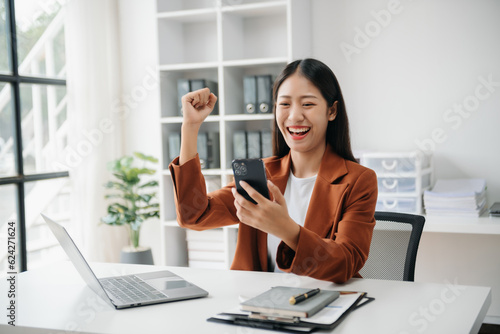 Asian business woman are delighted and happy with the work they do on their tablet, laptop and taking notes at the office..