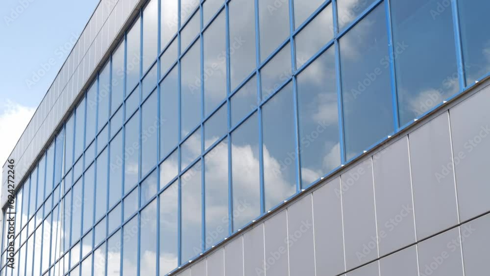 Blue sky with white clouds reflecting in windows of building, low angle view. Time-lapse Blue sky with white clouds reflecting in windows of building, low angle view. Time-lapse