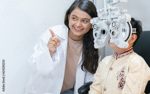 Indian child boy doing subjective refraction with diagnostic ophthalmology equipment, phoropter with ophthalmologist or optometrist or doctor for eyes vision exam test at hospital or clinic