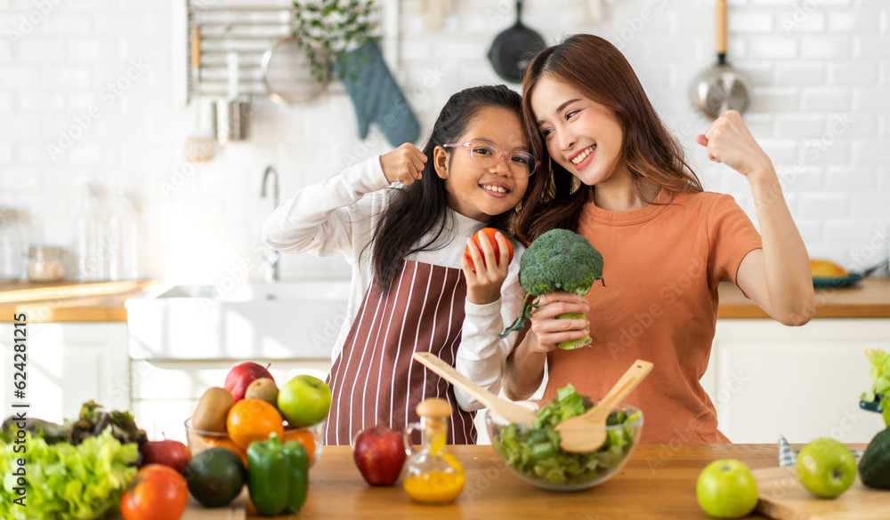 Portrait of enjoy happy love asian family mother and little asian girl daughter child having fun help cooking food healthy eat together with fresh vegetable salad and ingredient in kitchen Portrait of enjoy happy love asian family mother and little asian girl daughter child having fun help cooking food healthy eat together with fresh vegetable salad and ingredient in kitchen