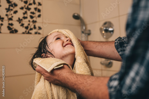 Father wiping happy son with towel in bathroom