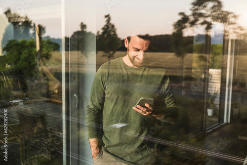 Man using smart phone seen through glass